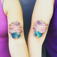 two women with matching tattoos on their arms holding cupcakes in the shape of hearts