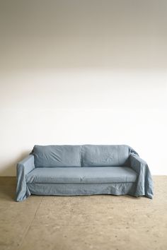 a blue couch sitting on top of a floor next to a white wall with a wooden frame