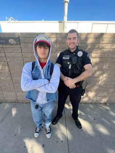 two police officers standing next to each other on the sidewalk with their arms crossed in front of them