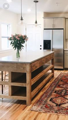 a kitchen with an island, sink and refrigerator in it's center area next to a rug