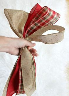 a hand holding a ribbon on top of a white furnishing floor next to a red and green plaid bow