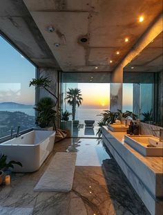 a bathroom with a large bathtub next to a window overlooking the ocean at sunset