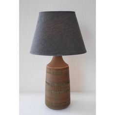 a lamp that is on top of a table with a gray shade over the base