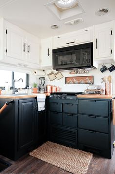 a kitchen with black cabinets and white walls is pictured in this image, there are pictures on the wall above the stove