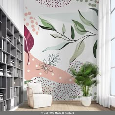 a white chair sitting in front of a book shelf next to a wall with leaves on it