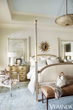 a bed room with a neatly made bed next to a chair and mirror on the wall