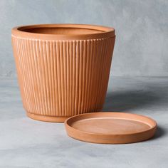 a clay pot and plate sitting next to each other on a gray surface with a grey background