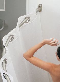 a woman brushing her hair in front of a shower curtain with rollers on it