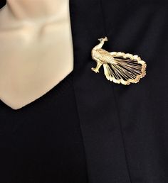 a close up of a person wearing a black shirt with a gold brooch on it