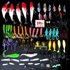 many different types of fishing lures are displayed on a black surface with white and green handles