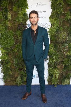 a man in a green suit standing on a blue carpet