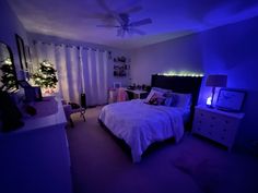 a bedroom is lit up with blue lights and white bedding, along with christmas trees