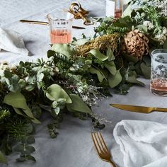 the table is decorated with greenery and goldware