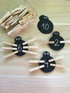 wooden pegs with faces and numbers on them sitting next to a container of clothes pins