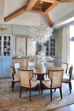 a dining room table with chairs and a chandelier hanging from it's ceiling