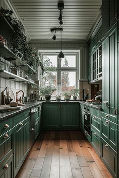 a kitchen filled with lots of green cabinets and wooden flooring next to a window