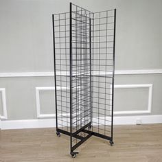 a tall black metal rack on wheels in a room with white walls and wood flooring