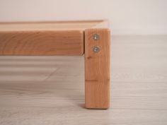 a wooden bench sitting on top of a hard wood floor next to a white wall