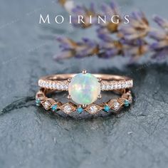 an opal and diamond ring on top of a stone