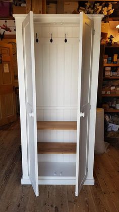 an open closet with shelves and hooks on the door, in a room that has wooden floors