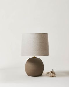 a table lamp with a white shade on it and a cord plugged into the base