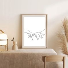 two hands pointing towards each other in black and white framed art print on wall above bed