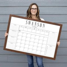 a woman holding up a large calendar board