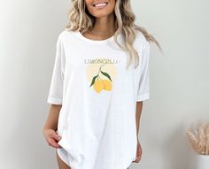 "Add a zesty twist to your wardrobe with our \"Limoncello\" t-shirt, capturing the refreshing essence of this vibrant Italian classic. This comfortable tee is the perfect blend of style and comfort, inviting you to savor the simple pleasures of life. .: 100% Airlume combed and ringspun cotton (fiber content may vary for different colors) .: Light fabric (4.2 oz/yd² (142 g/m .: Retail fit .: Tear away label .: Runs true to size" White Short Sleeve T-shirt With Lemon Print, Casual Lemon Tops For Summer, Short Sleeve Lemon Print Graphic Tee, White Short Sleeve Top With Lemon Print, White Crew Neck T-shirt With Lemon Print, White Lemon Print T-shirt For Summer, Casual Crew Neck Top With Lemon Print, Spring Lemon Print Short Sleeve Tops, Casual Relaxed Fit Lemon Print Tops