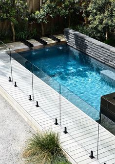 an above ground swimming pool surrounded by plants and trees with water running down the side