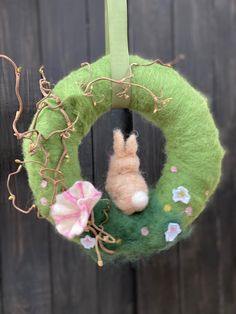 a green wreath with a small stuffed animal hanging from it