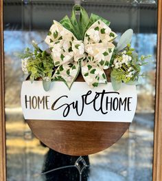 a sign that says home sweethome with flowers in the center and greenery on top