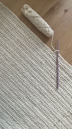 a crocheted rug with a knitting needle next to it