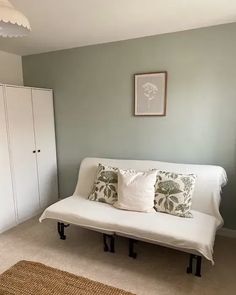 a white couch sitting in a living room next to a cabinet and rug on the floor