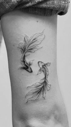 a woman's lower back tattoo with two goldfishs