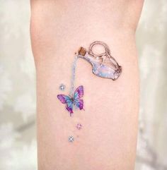 a small butterfly tattoo on the side of a woman's thigh, with a bottle and butterflies attached to it