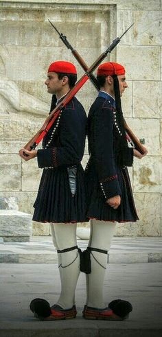 two men in uniforms with red berets and swords standing next to each other