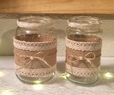 two mason jars with lace and lights on the lids are sitting next to each other