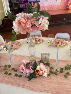 the table is set with pink flowers and place settings for two people to sit at