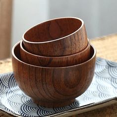 four wooden bowls sitting on top of a plate next to chopsticks and fork