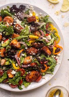 a white plate topped with a salad covered in lots of veggies and feta cheese