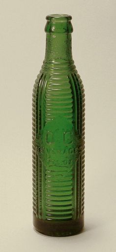 a green glass bottle sitting on top of a table