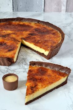 two slices of cheesecake sitting on top of a marble counter next to a cup