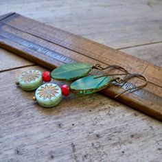 A little bit of seafoam green, a little turquoise, and a tiny pop of red coral make these earrings stand out from the crowd. My daughter described them as "artsy" or "boho." I think they are just fun!The bottom bead is a 12mm coin bead with a bronze aster flower design. The larger bead is a milky aqua bead. It is 8 x 19mm in size and ranges from transparent to a more solid color depending on the bead. I do match them up, so they go together. The coral red is a 6x4mm faceted bead. All are beautif Adjustable Jade Beaded Earrings As A Gift, Jade Earrings With Dangling Beads As A Gift, Beaded Jade Earrings As A Gift, Jade Beaded Earrings With Ear Wire For Gifts, Jade Beaded Earrings With Ear Wire As Gift, Jade Beaded Earrings As Gift, Jade Beaded Drop Earrings, Adjustable Green Bohemian Beaded Earrings, Turquoise Czech Glass Round Bead Earrings