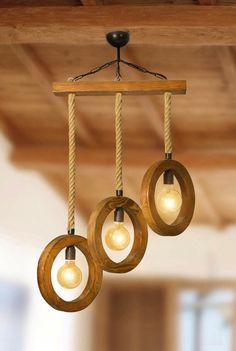 three lights hanging from a wooden beam with rope and wood circles around them on the ceiling