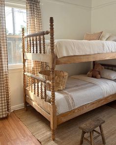 a wooden bunk bed sitting in a bedroom next to a window with checkered curtains