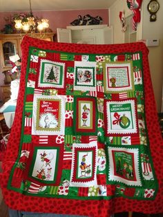 a woman holding up a christmas quilt in her kitchen with santa's helpers on it