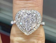 a heart shaped diamond ring on someone's finger