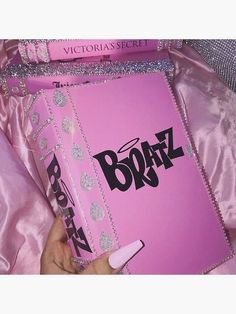 a person is holding a pink book in their hand and it's surrounded by shiny material