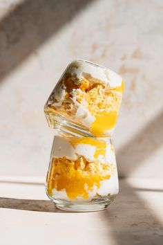 two desserts are stacked on top of each other in small glass containers with yellow and white toppings