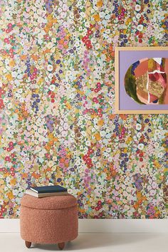 a room with a flowered wallpaper and a small ottoman in front of it